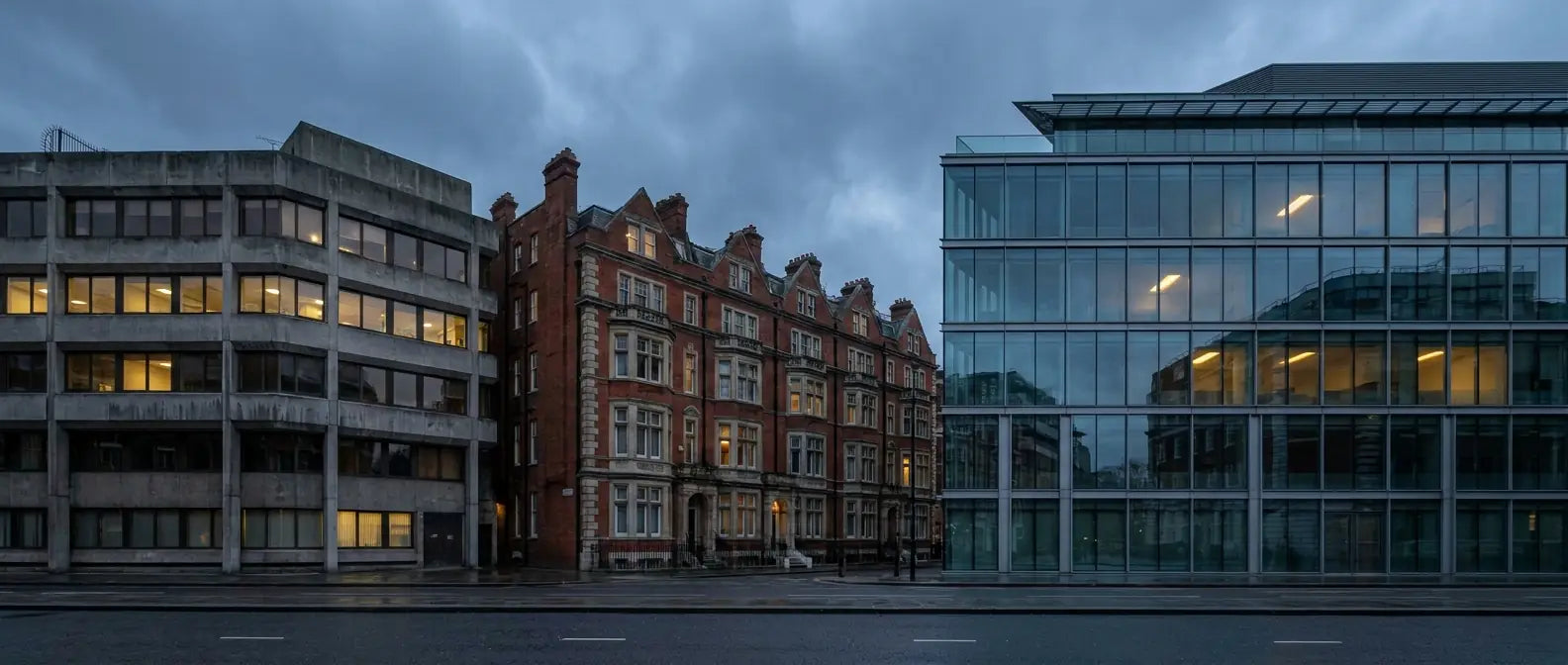 Concrete, red-brick and glass commercial buildings side by side on a London street at dusk
